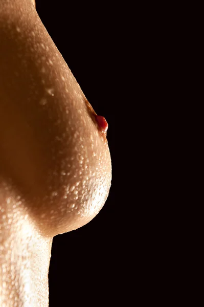 stock image Female breast in front of black background