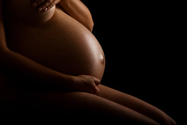 stock image Nude pregnant woman belly on black background